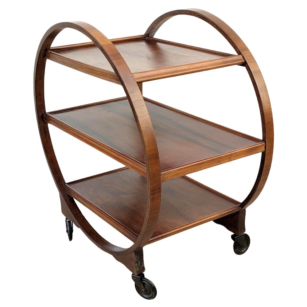 An Art Deco circular walnut drinks trolley featuring three rectangular tiers enclosed within a sweeping circular frame on small castors. View VII