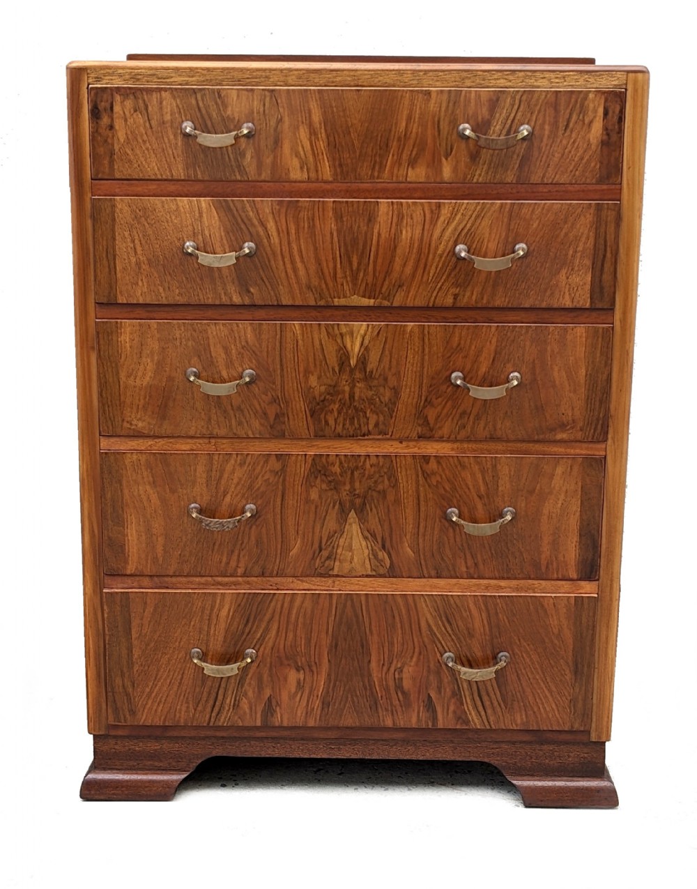 An Art Deco walnut chest featuring five graduated drawers with bookmatched wood grain and curved brass handles.