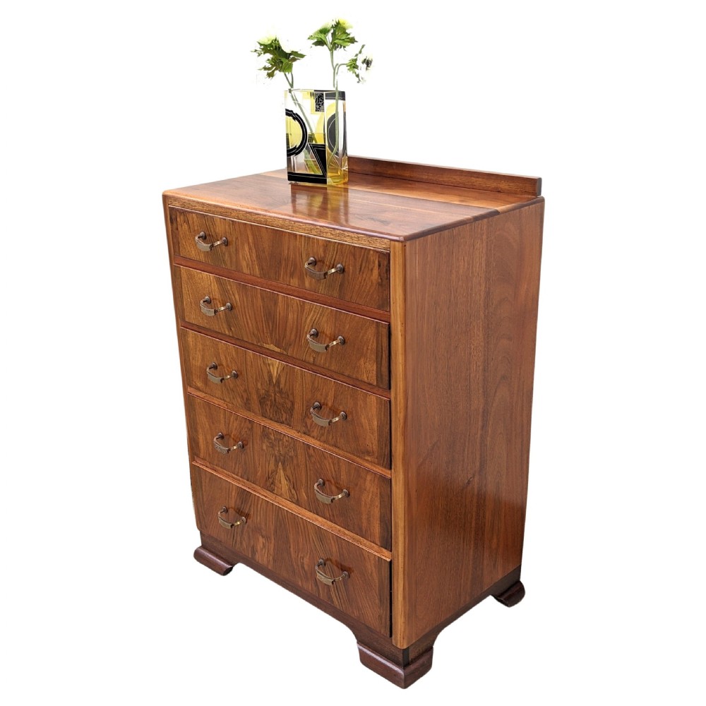 An Art Deco walnut chest featuring five graduated drawers with bookmatched wood grain and curved brass handles. View II