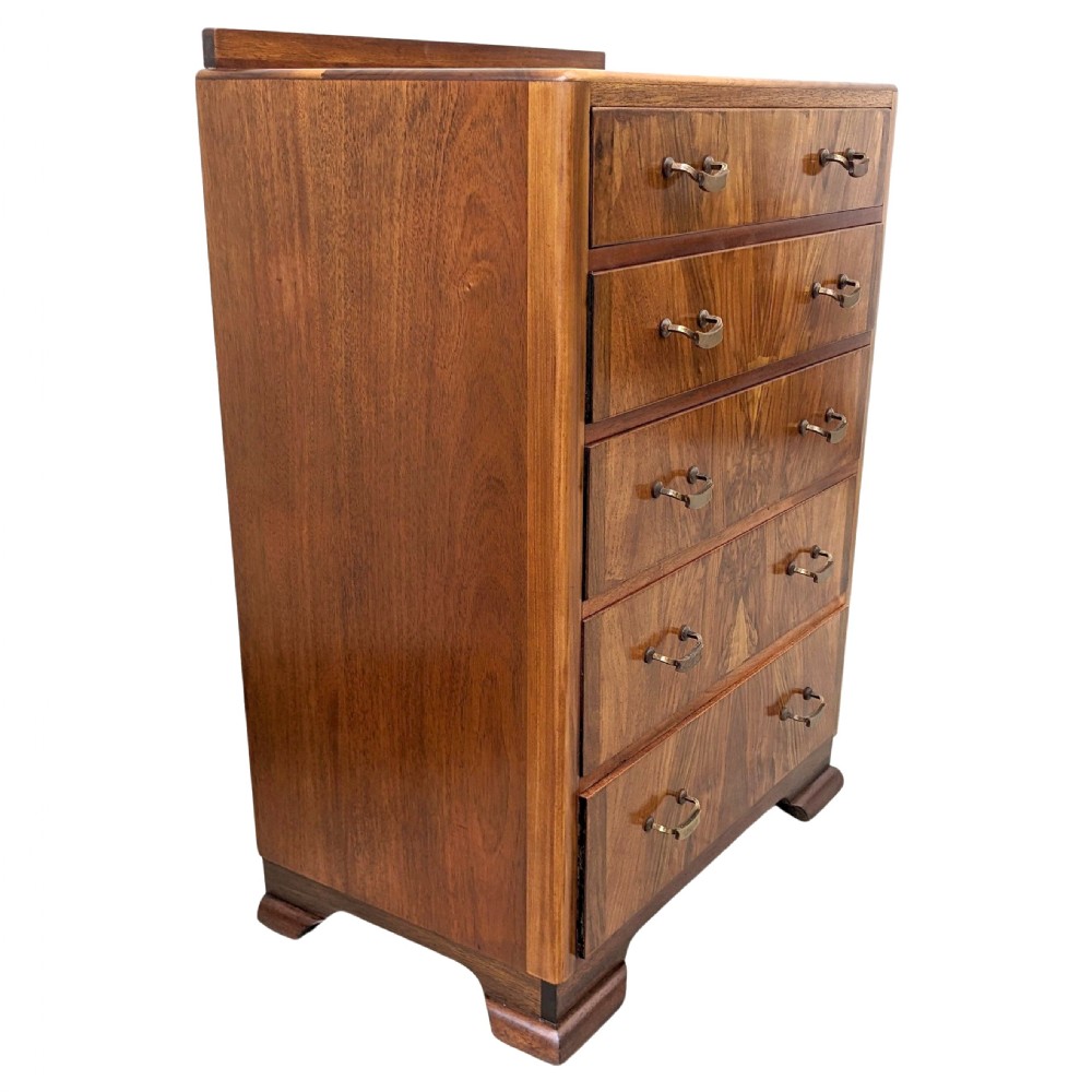 An Art Deco walnut chest featuring five graduated drawers with bookmatched wood grain and curved brass handles. View VII