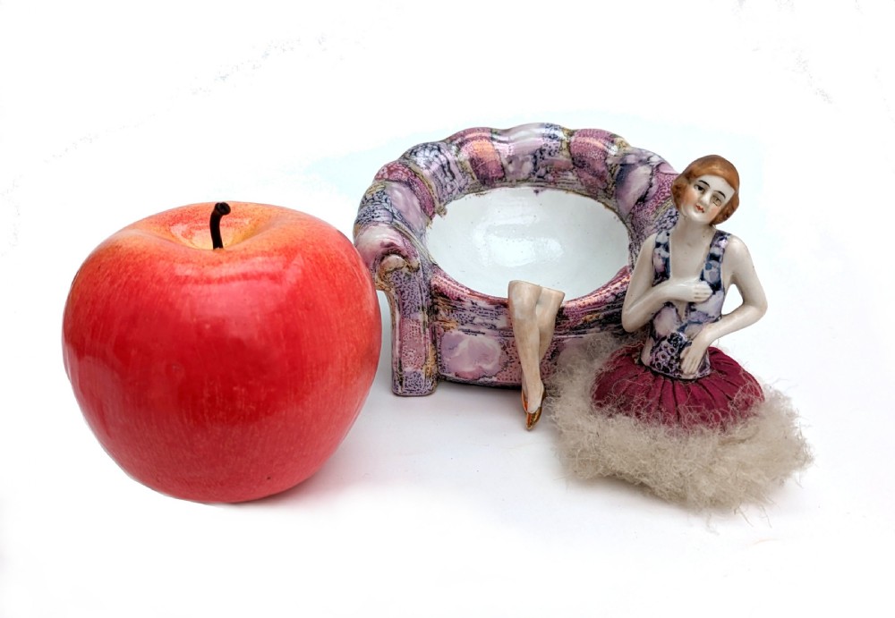 An Art Deco glazed ceramic powder puff stand modelled as a flapper lady seated in a pink and purple mottled armchair. View VI
