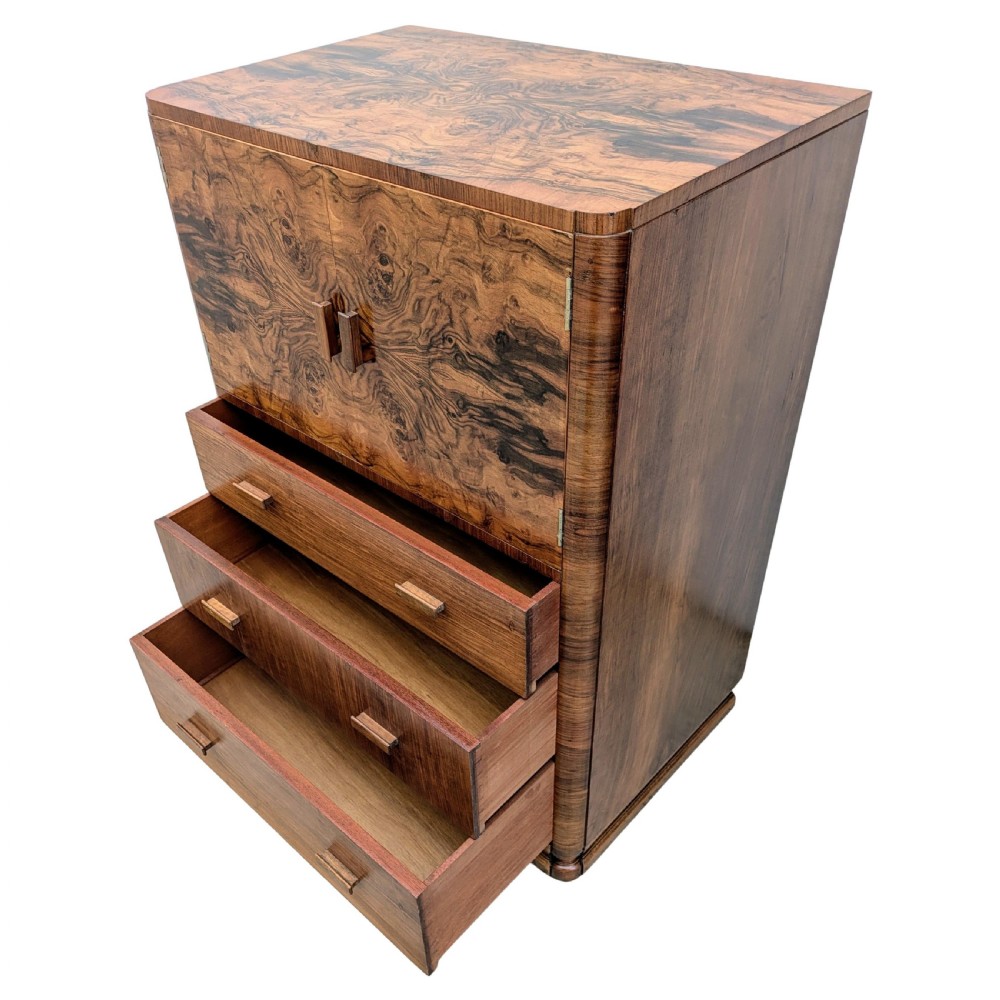 An English Art Deco tallboy crafted from figured burr walnut, featuring a top two-door cupboard above three full-width drawers with matching handles. View V