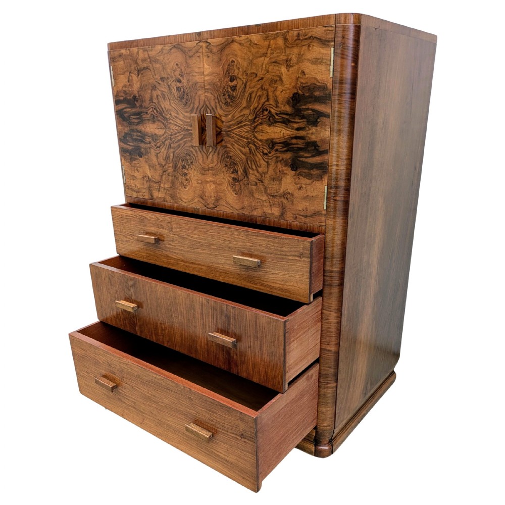 An English Art Deco tallboy crafted from figured burr walnut, featuring a top two-door cupboard above three full-width drawers with matching handles. View VI