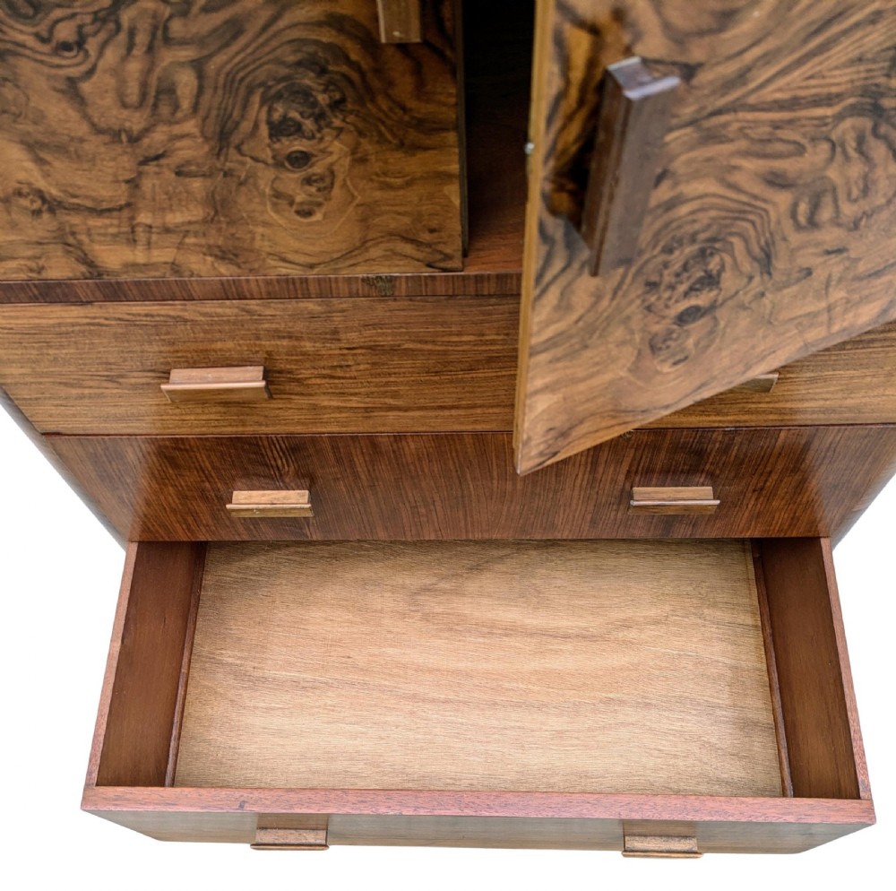 An English Art Deco tallboy crafted from figured burr walnut, featuring a top two-door cupboard above three full-width drawers with matching handles. View XII
