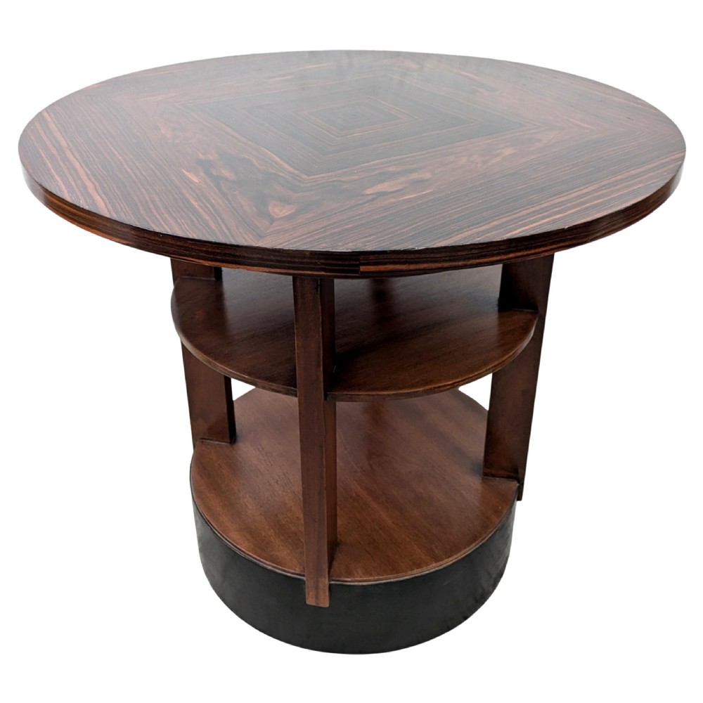 An Art Deco circular dark wood centre table featuring three tiered shelves supported by four vertical legs resting on a solid round base. View IX