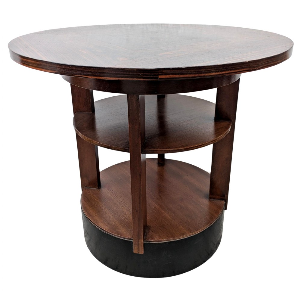 An Art Deco circular dark wood centre table featuring three tiered shelves supported by four vertical legs resting on a solid round base. View X