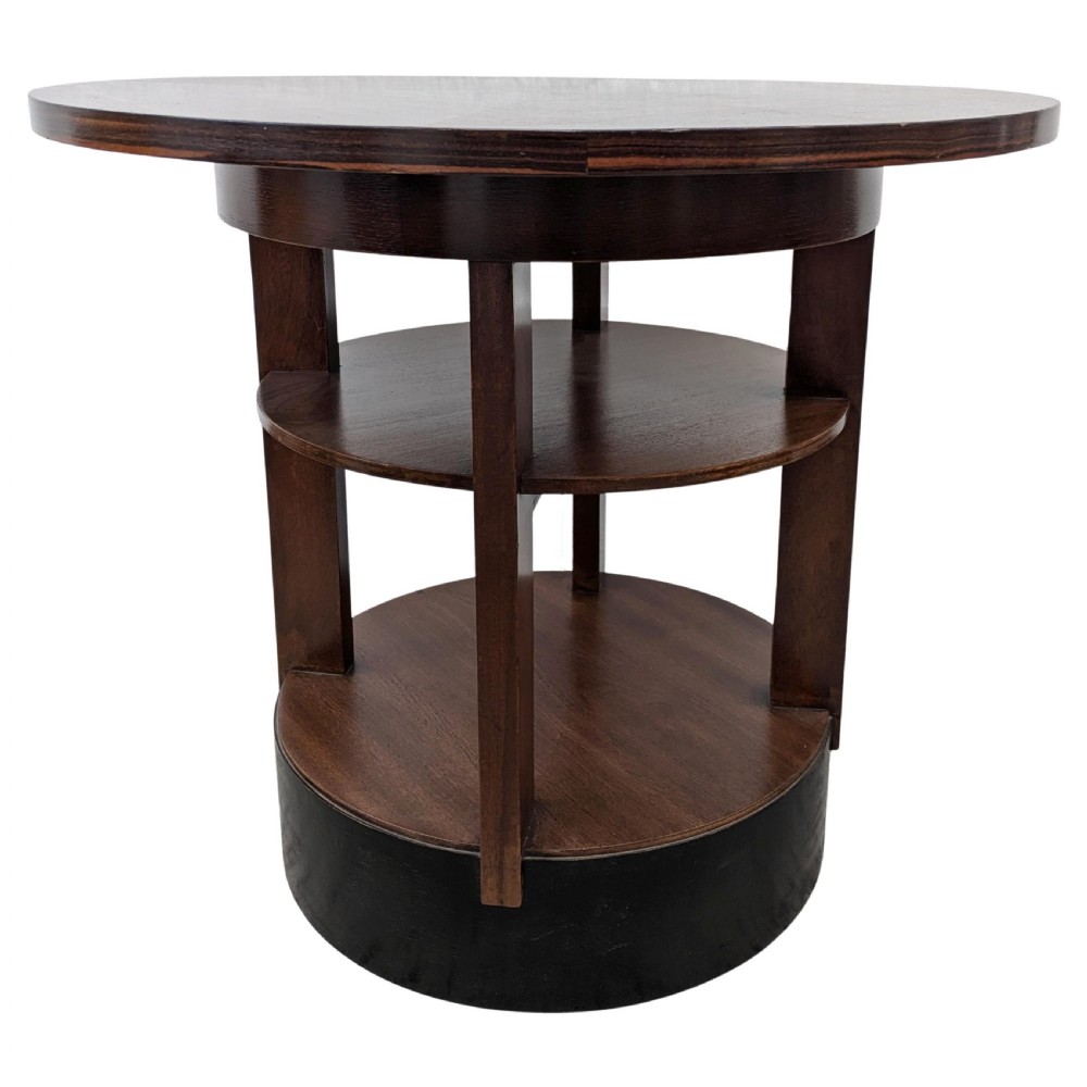An Art Deco circular dark wood centre table featuring three tiered shelves supported by four vertical legs resting on a solid round base. View XI