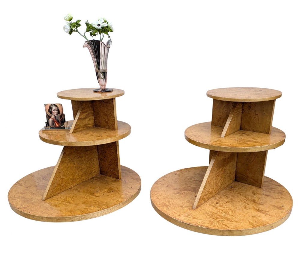 A matching pair of British Art Deco three-tiered modernist occasional tables featuring figured light brown wood veneer and architectural angular supports. View VI