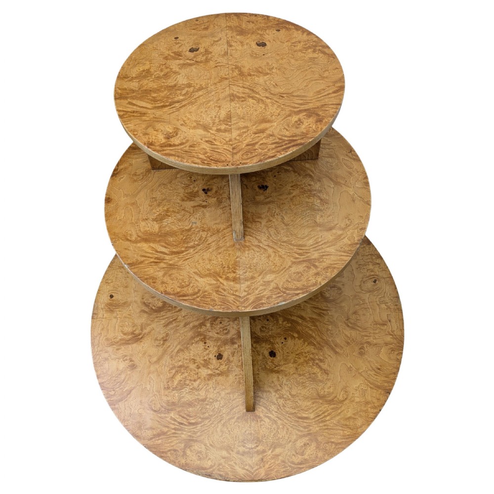 A matching pair of British Art Deco three-tiered modernist occasional tables featuring figured light brown wood veneer and architectural angular supports. View VIII