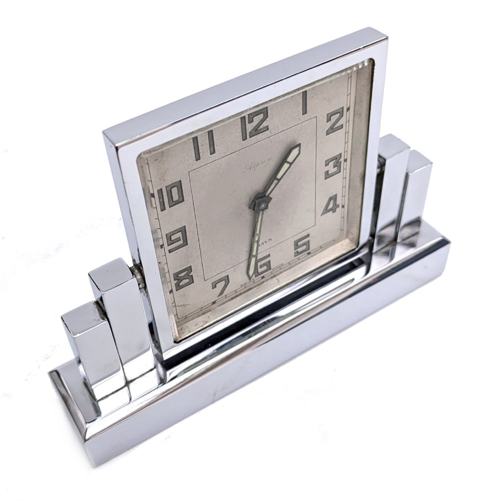 An Art Deco chrome desk clock featuring a rectangular face with geometric stepped side columns and stylized numerals. View V