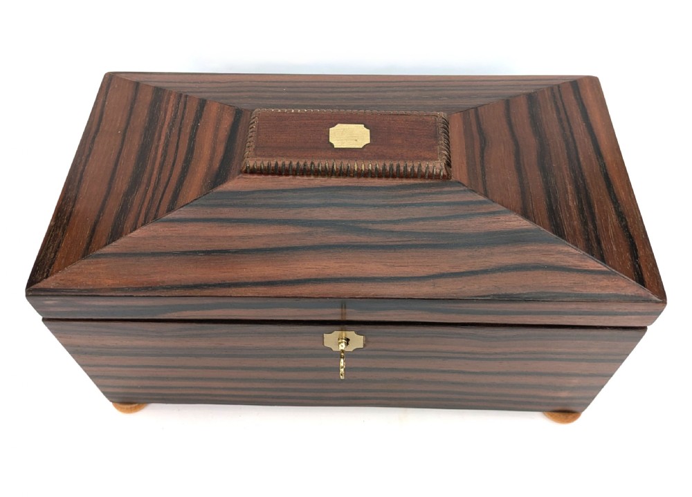 An open Art Deco dark wood tea caddy featuring a light wood sunburst inlay pattern on its internal lid. View X