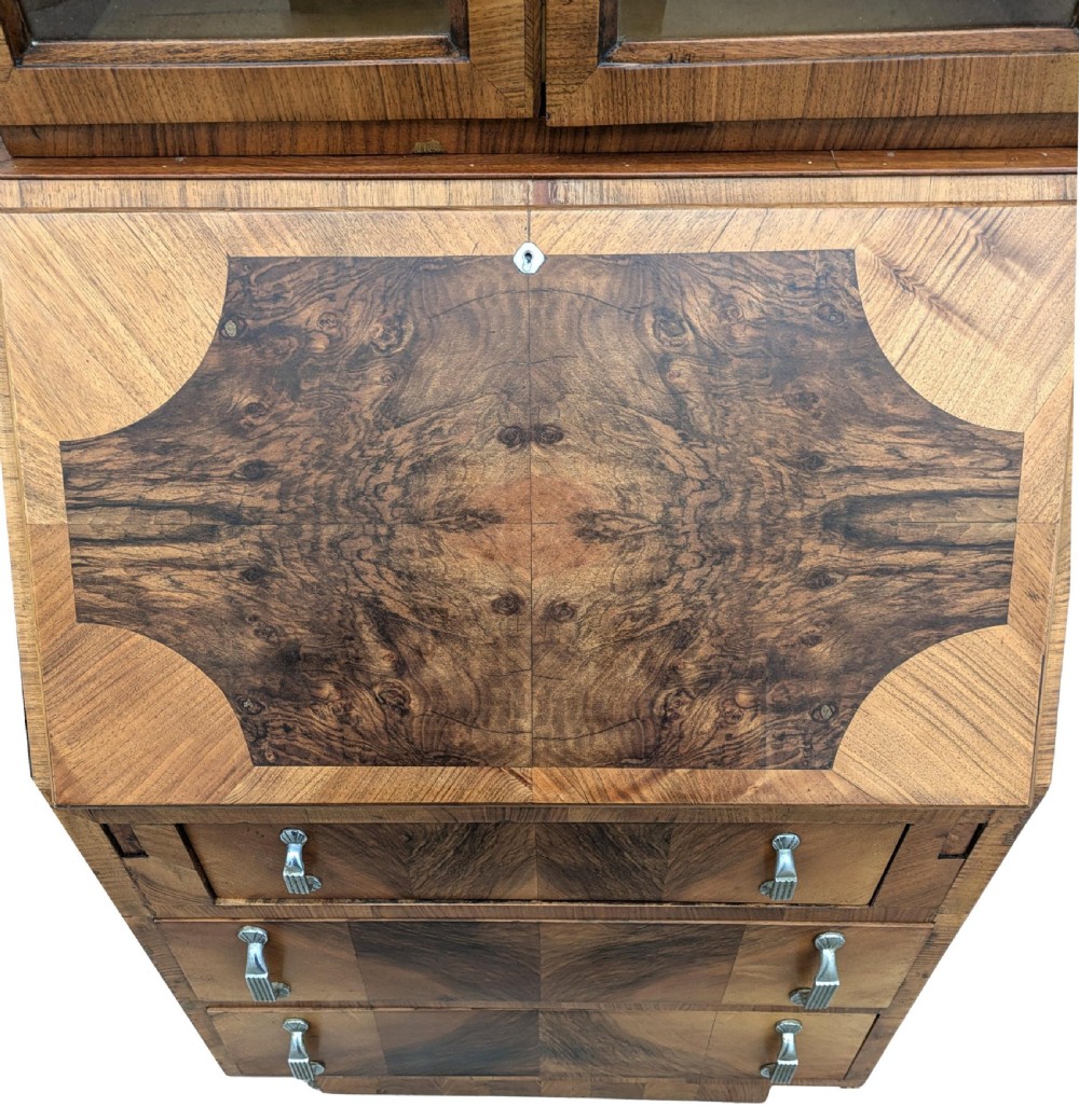 An Art Deco walnut upright bureau bookcase featuring a two-door glazed upper display cabinet above a slope-front writing slope and three drawers. View XII