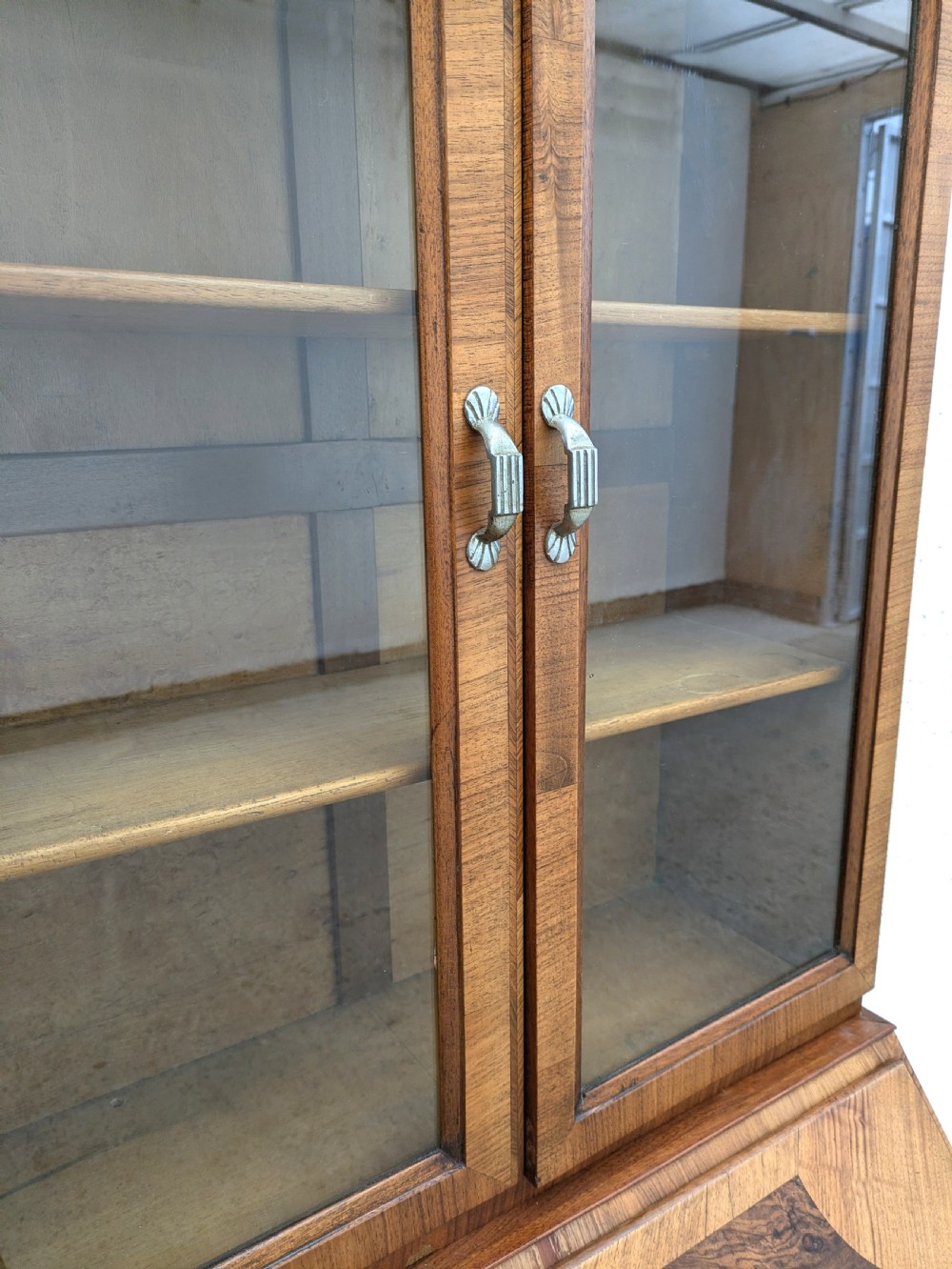An Art Deco walnut upright bureau bookcase featuring a two-door glazed upper display cabinet above a slope-front writing slope and three drawers. View XIII