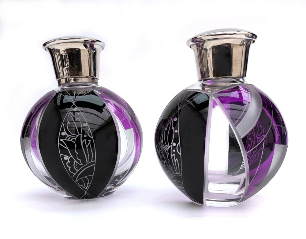 A pair of spherical glass Art Deco perfume bottles featuring purple and black geometric enamel panels with etched floral patterns and polished metal caps. View III