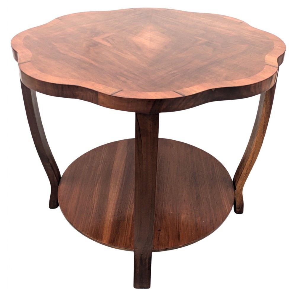 An Art Deco two-tier coffee table in figured walnut with a scalloped top, crossbanded border, circular lower shelf, and curved legs. View VI