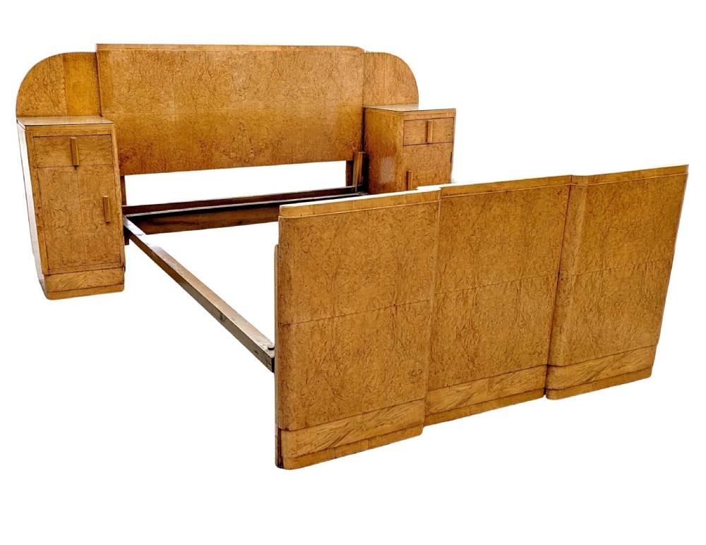 A 1930s Art Deco double bedstead crafted from blonde maple veneer featuring an arched headboard with integrated bedside cabinets and a matching stepped footboard.