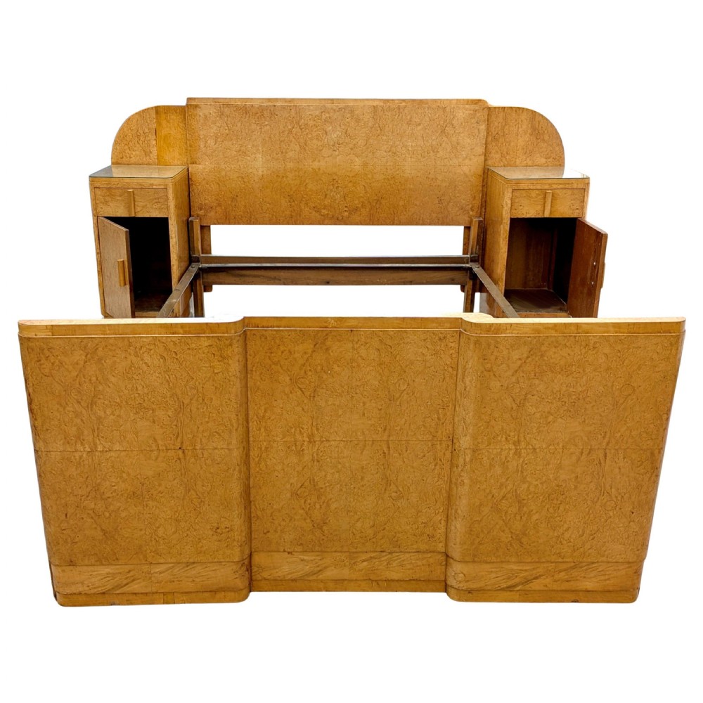 A 1930s Art Deco double bedstead crafted from blonde maple veneer featuring an arched headboard with integrated bedside cabinets and a matching stepped footboard. View X