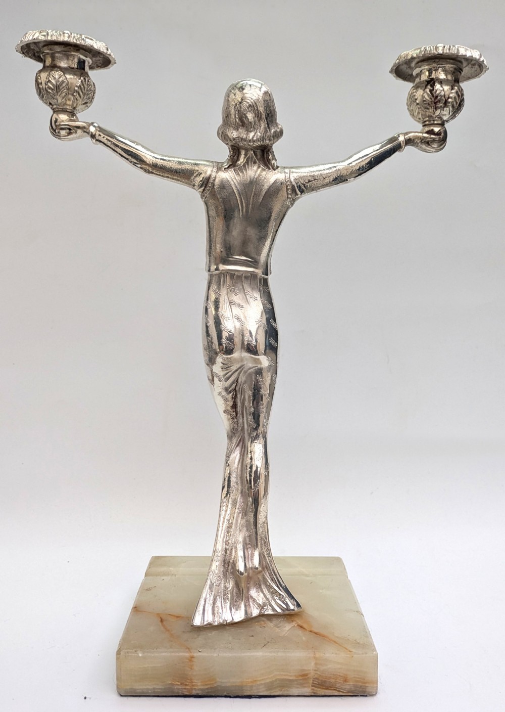 An Art Deco silvered spelter candelabra featuring a female figure holding two candle cups, standing on a square onyx base. View II