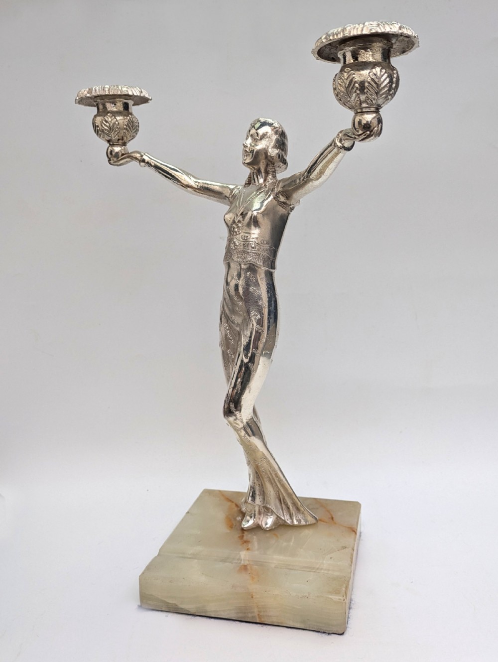 An Art Deco silvered spelter candelabra featuring a female figure holding two candle cups, standing on a square onyx base. View III