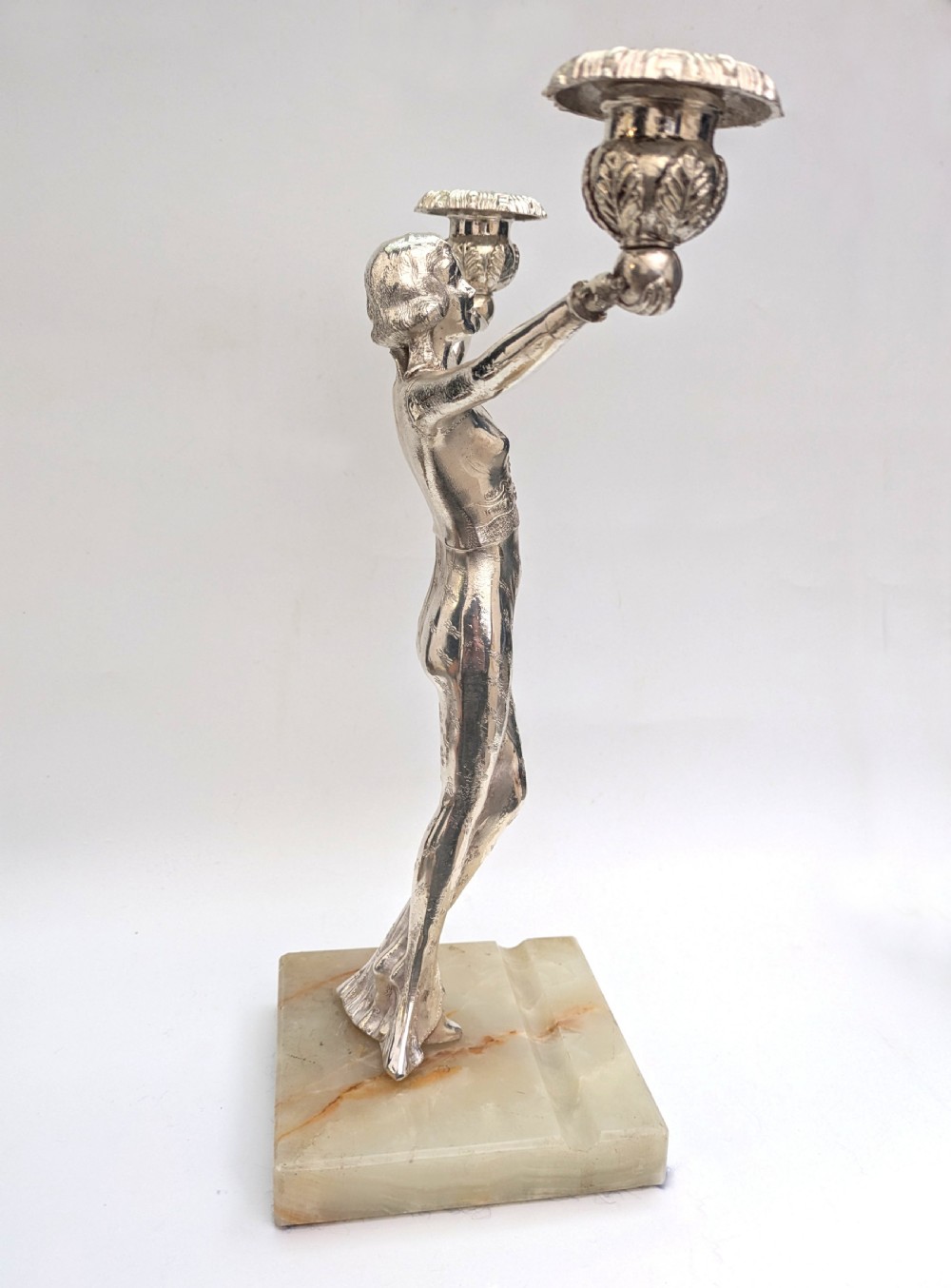 An Art Deco silvered spelter candelabra featuring a female figure holding two candle cups, standing on a square onyx base. View V