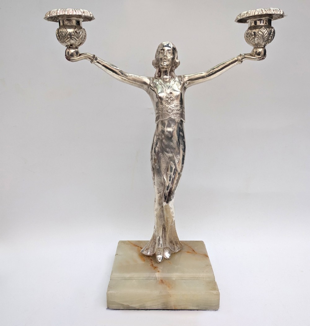 An Art Deco silvered spelter candelabra featuring a female figure holding two candle cups, standing on a square onyx base. View VIII