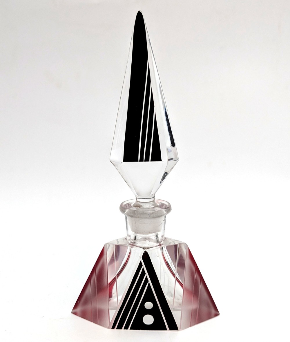 An Art Deco clear and frosted glass perfume bottle featuring a tall faceted stopper and black enamelled geometric designs.