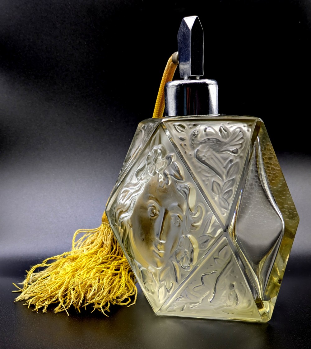 A faceted clear glass Art Deco scent bottle featuring a relief-moulded womans face and a gold fabric atomiser bulb with tassel. View III