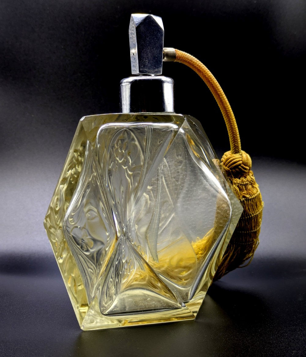 A faceted clear glass Art Deco scent bottle featuring a relief-moulded womans face and a gold fabric atomiser bulb with tassel. View V
