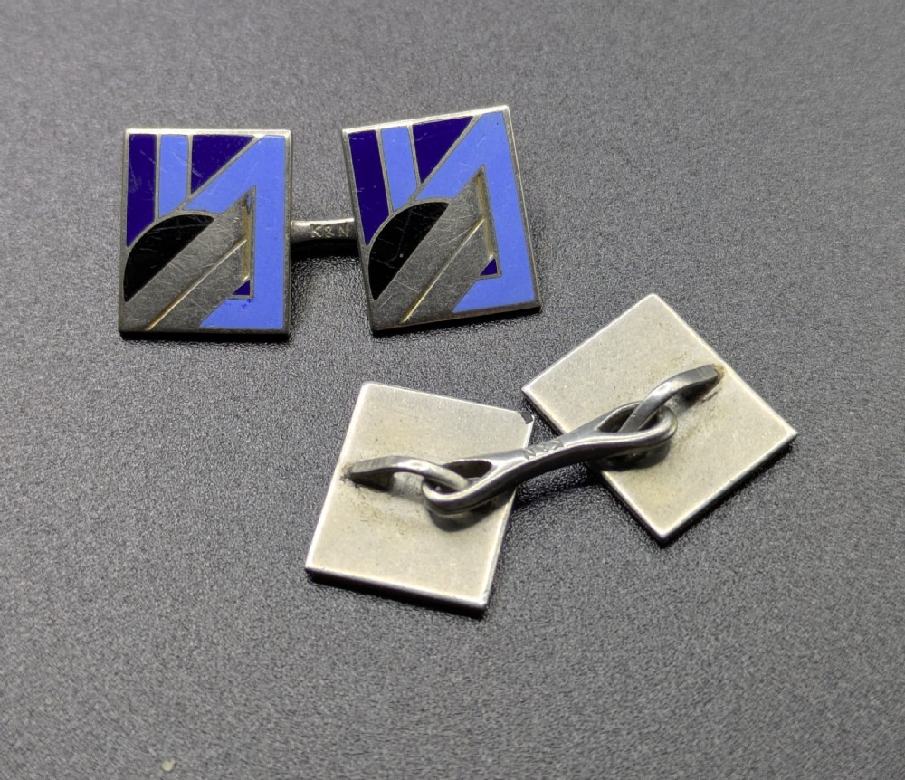 A matching pair of rectangular Art Deco enamel cufflinks featuring geometric patterns in shades of blue, black, and silver-tone metal. View V