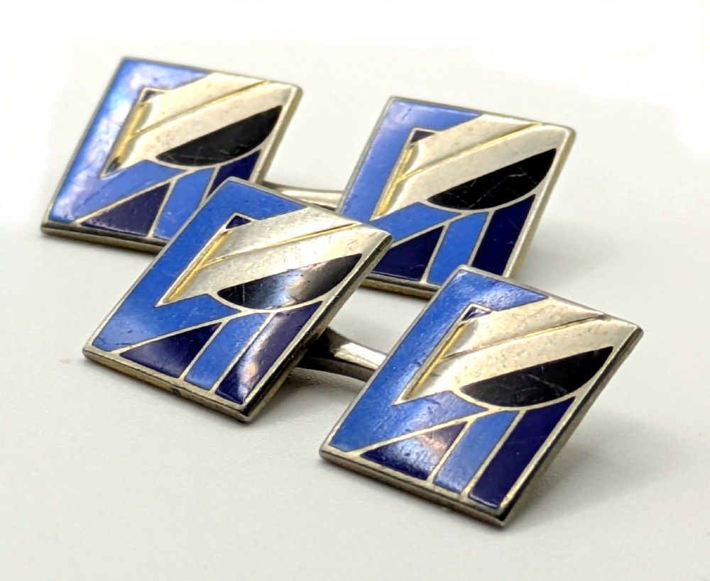 A matching pair of rectangular Art Deco enamel cufflinks featuring geometric patterns in shades of blue, black, and silver-tone metal. View VII