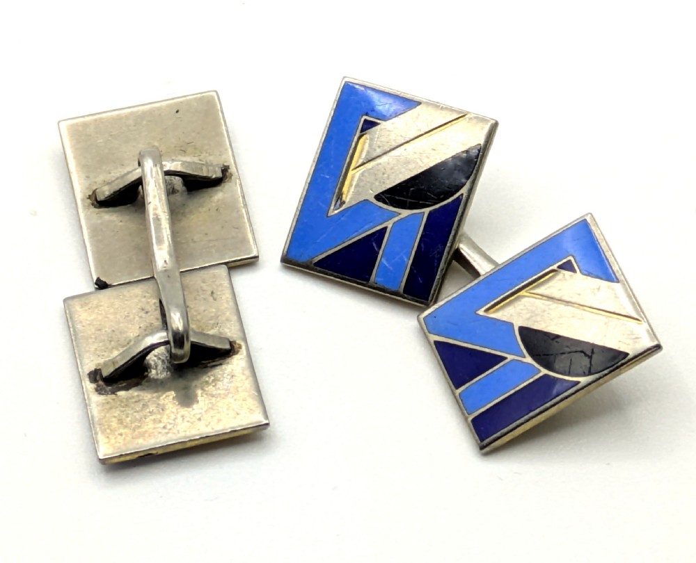 A matching pair of rectangular Art Deco enamel cufflinks featuring geometric patterns in shades of blue, black, and silver-tone metal. View IX