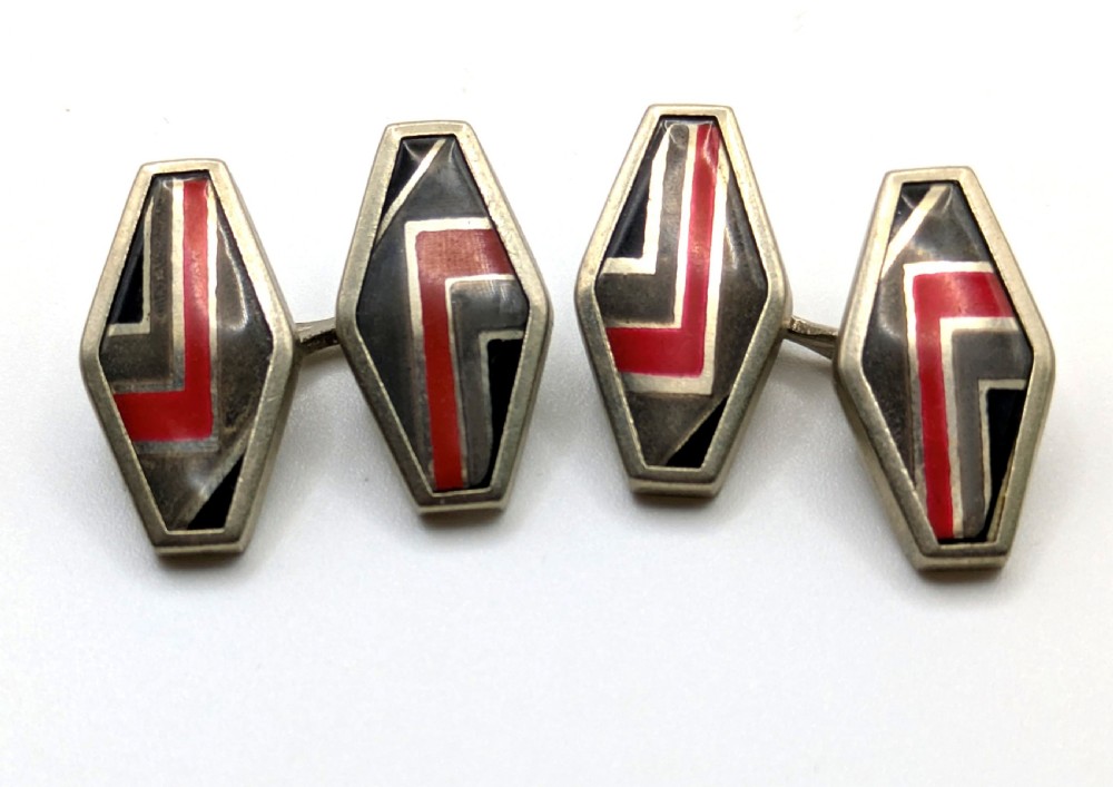 A pair of double-sided Art Deco silver cufflinks with geometric red, grey, and black enamel chevron detailing.