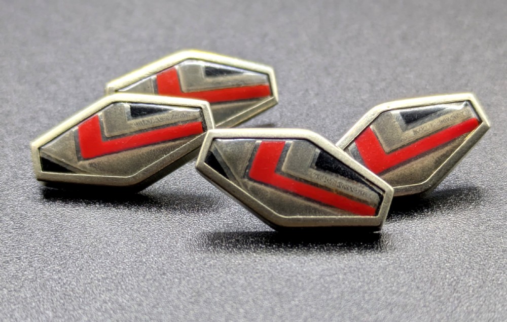 A pair of double-sided Art Deco silver cufflinks with geometric red, grey, and black enamel chevron detailing. View V
