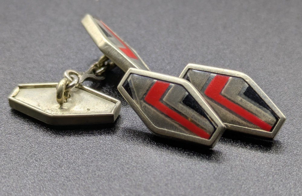 A pair of double-sided Art Deco silver cufflinks with geometric red, grey, and black enamel chevron detailing. View VI
