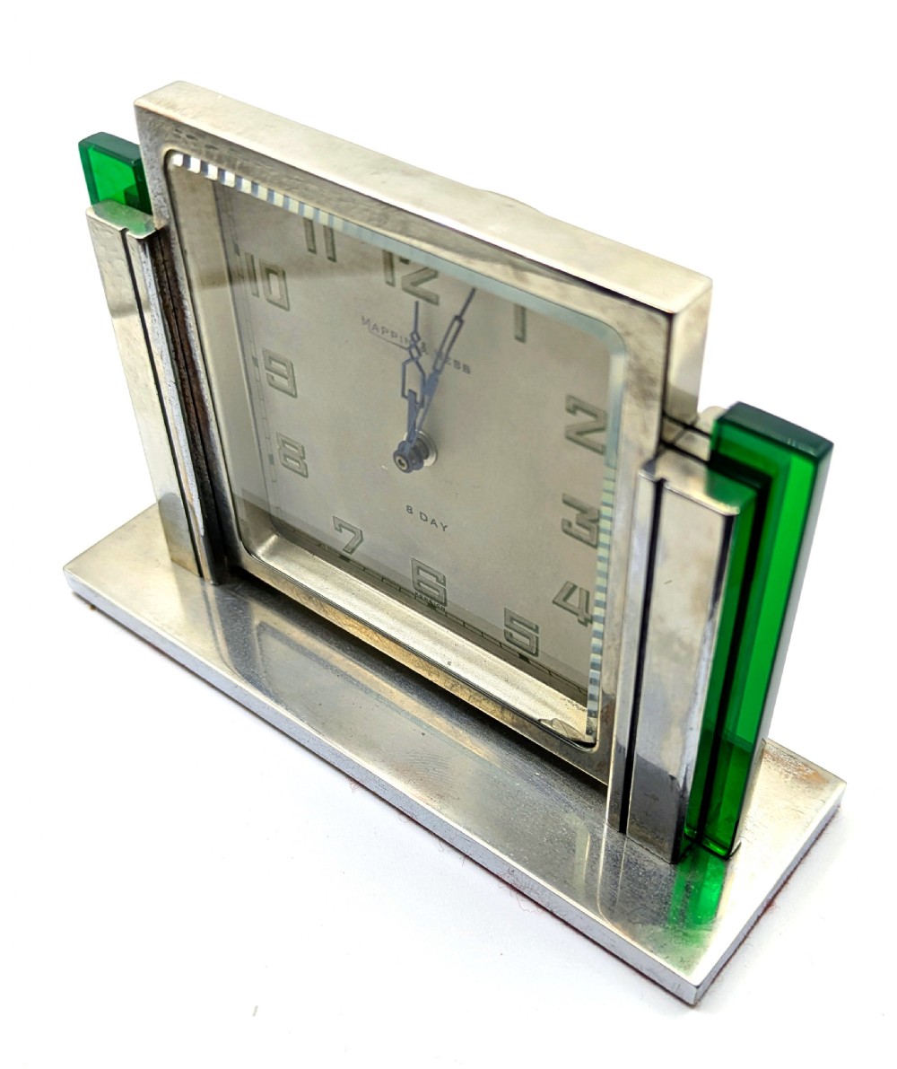 An Art Deco chrome-plated rectangular desk clock featuring green glass side accents and a square dial with geometric numerals. View IX