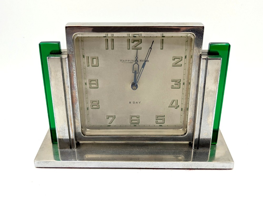 An Art Deco chrome-plated rectangular desk clock featuring green glass side accents and a square dial with geometric numerals. View X