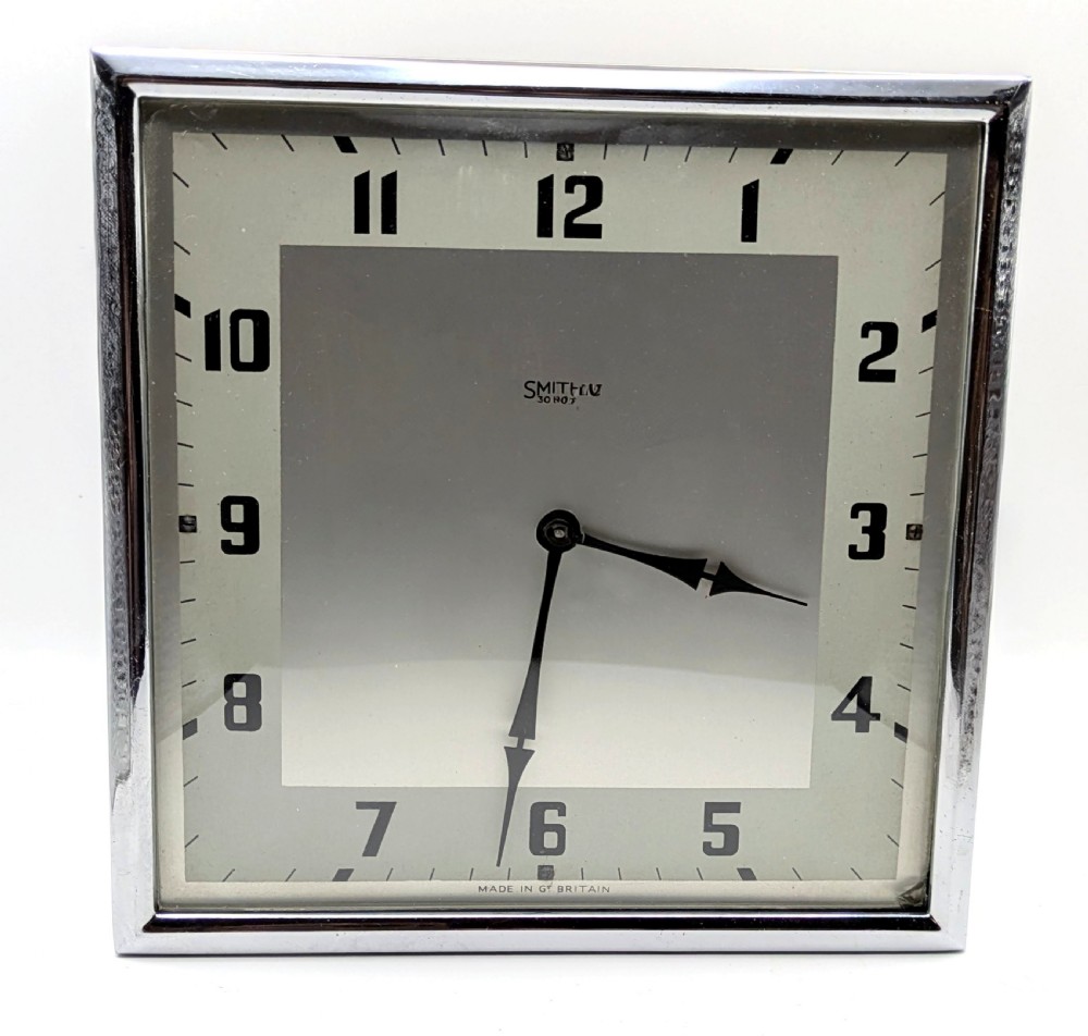 A square Art Deco chrome-framed easel clock featuring bold black Arabic numerals on a two-tone silver dial.