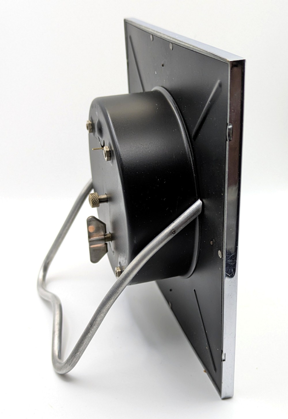 A square Art Deco chrome-framed easel clock featuring bold black Arabic numerals on a two-tone silver dial. View VI