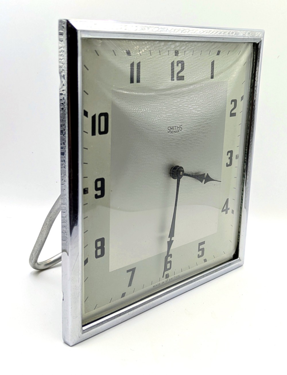 A square Art Deco chrome-framed easel clock featuring bold black Arabic numerals on a two-tone silver dial. View VIII