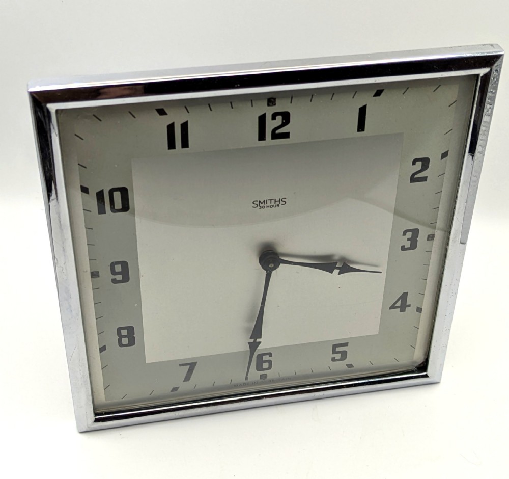 A square Art Deco chrome-framed easel clock featuring bold black Arabic numerals on a two-tone silver dial. View IX