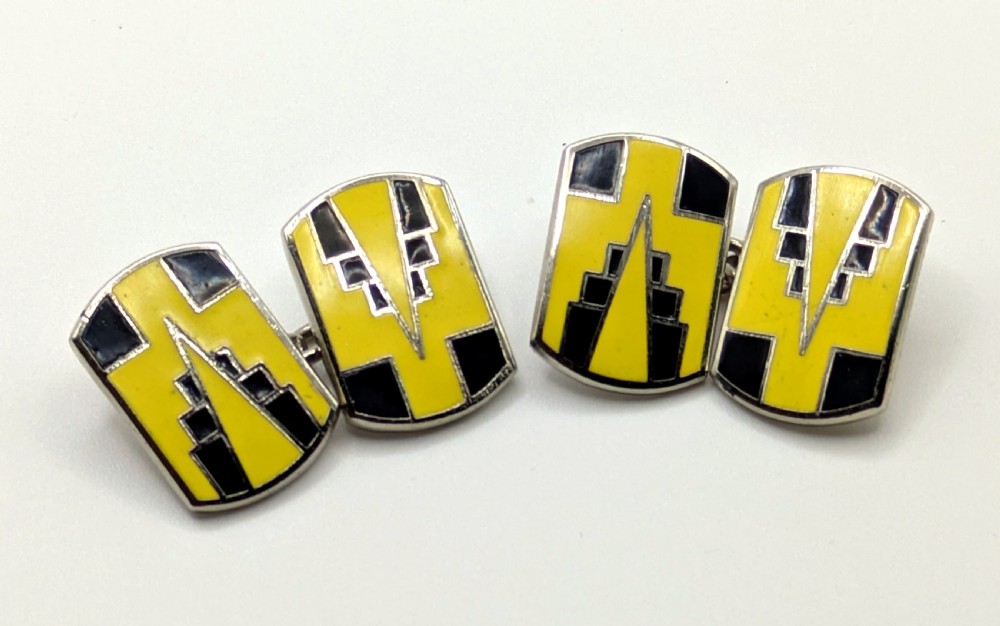 A pair of double-ended Art Deco cufflinks featuring geometric yellow and black enamel designs on silver metal mountings.