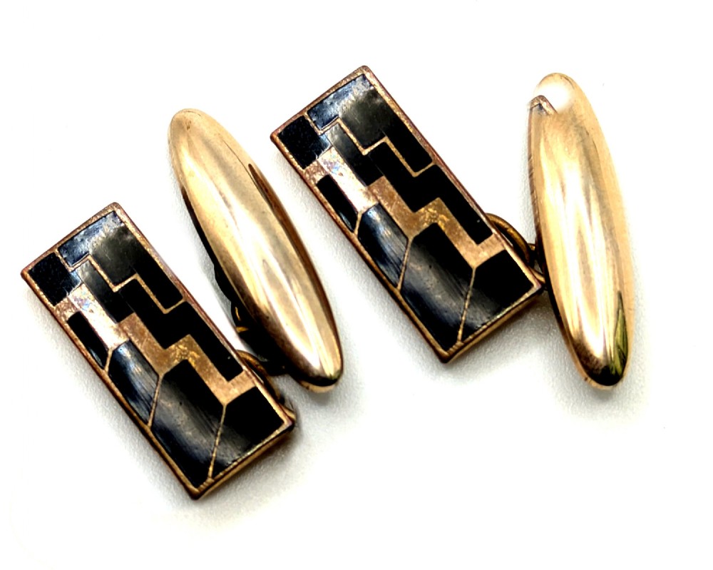 A pair of Art Deco rose gold tone cufflinks with rectangular black enamel geometric panels and torpedo backings.