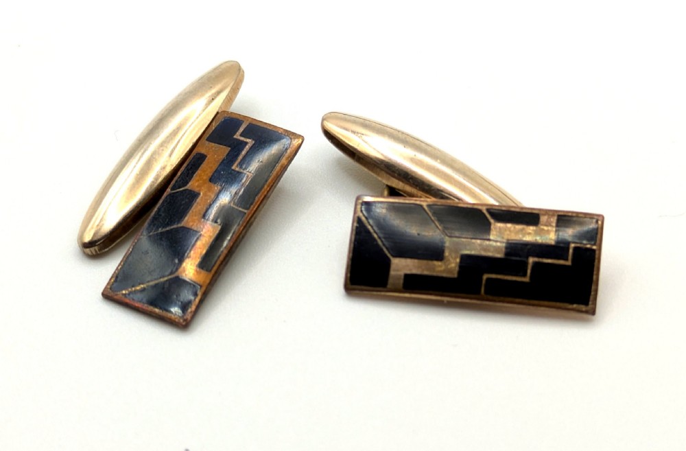 A pair of Art Deco rose gold tone cufflinks with rectangular black enamel geometric panels and torpedo backings. View IV