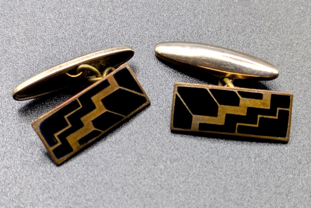 A pair of Art Deco rose gold tone cufflinks with rectangular black enamel geometric panels and torpedo backings. View V