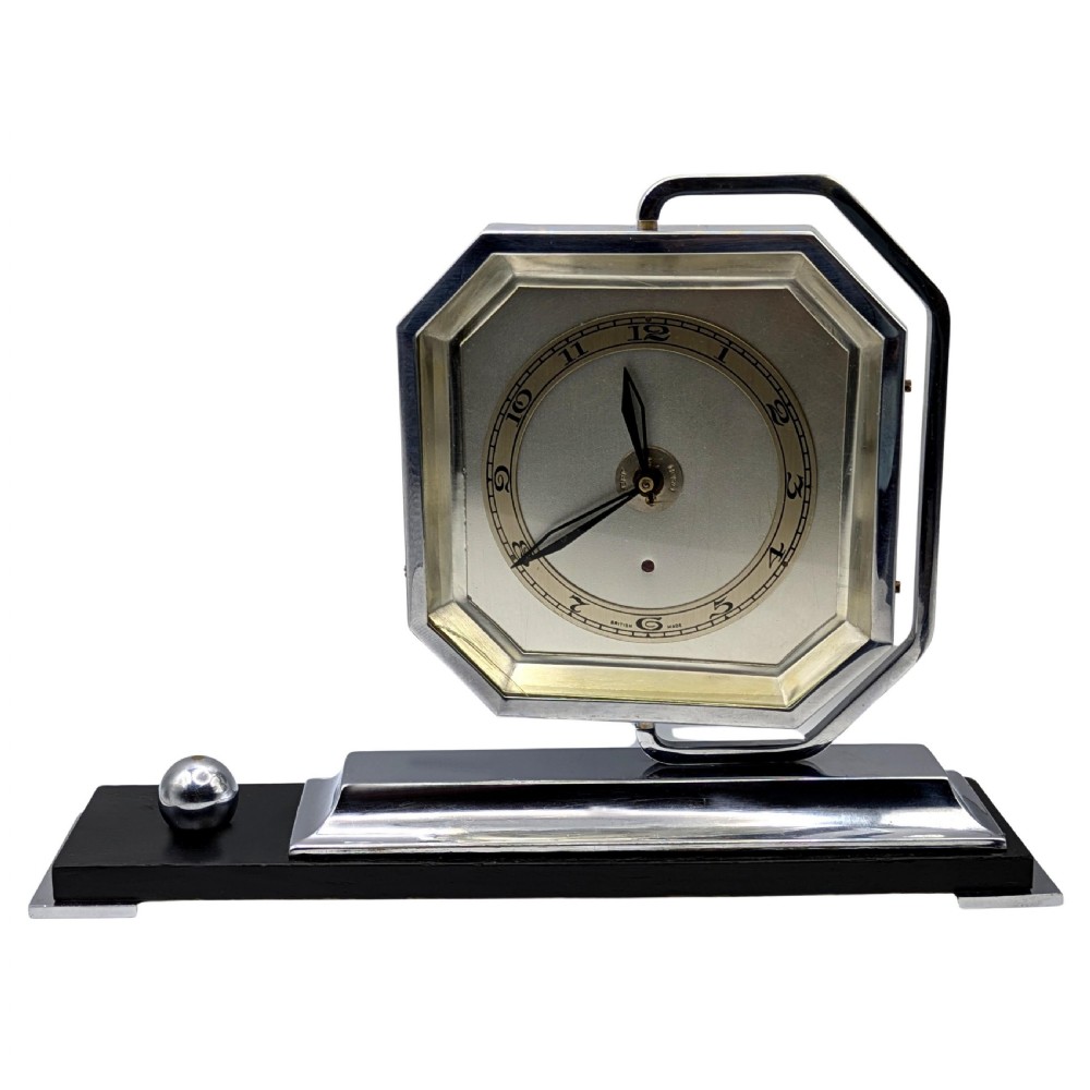An Art Deco desk clock featuring an octagonal chrome frame mounted on a stepped base with an ebonised plinth and a small chrome sphere detail.