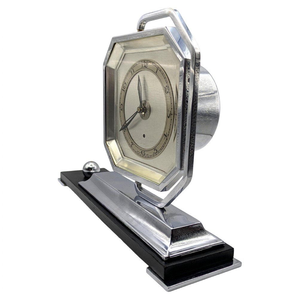An Art Deco desk clock featuring an octagonal chrome frame mounted on a stepped base with an ebonised plinth and a small chrome sphere detail. View III
