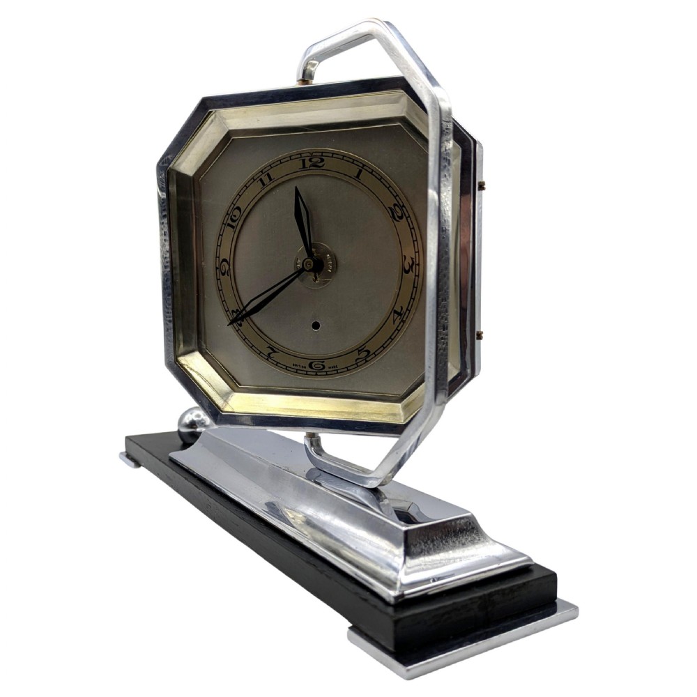 An Art Deco desk clock featuring an octagonal chrome frame mounted on a stepped base with an ebonised plinth and a small chrome sphere detail. View IV