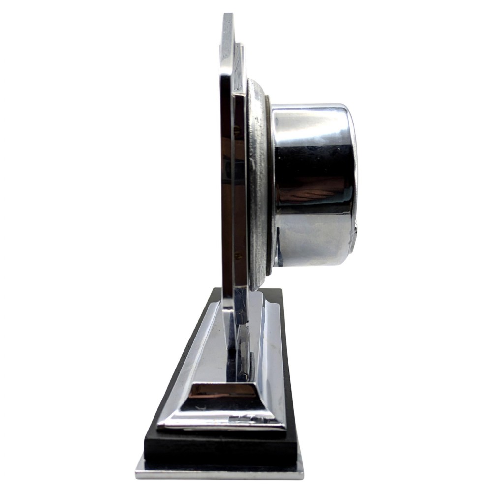 An Art Deco desk clock featuring an octagonal chrome frame mounted on a stepped base with an ebonised plinth and a small chrome sphere detail. View VI