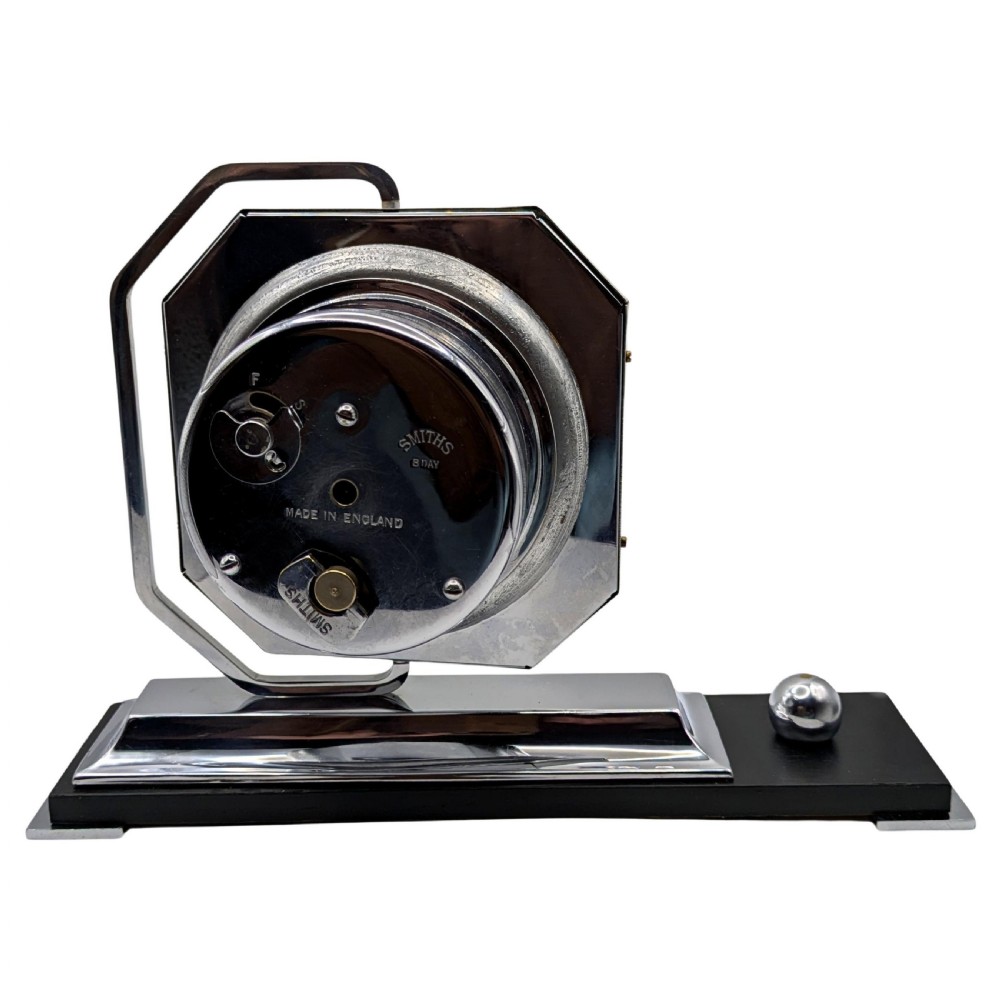 An Art Deco desk clock featuring an octagonal chrome frame mounted on a stepped base with an ebonised plinth and a small chrome sphere detail. View IX