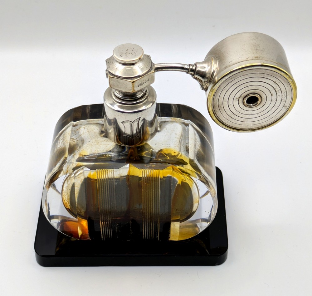 A French Art Deco cut glass perfume atomiser featuring a silver-toned metal spray mechanism mounted on a flat black rectangular base. View II